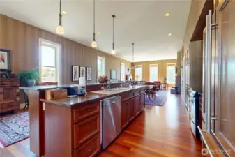 This gourmet kitchen features custom cabinetry with a rich wood finish, sleek granite countertops, and high-end stainless-steel appliances—including a built-in microwave, gas range, and panel-front refrigerator that blends seamlessly into the design.