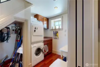 Laundry room – stacked washer/dryer, upper and lower cabinets, under-stair storage.