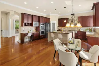 Adjacent to the formal dining room, the dream kitchen boasts high-end appliances, including a Bosch refrigerator and dishwasher. Highlights include a stylish tiled backsplash, glass pantry door, spacious central island with cabinetry, slab granite countertops, and an elegant breakfast nook that flows from the family room to the outdoor retreat. Abundant natural light completes the space.