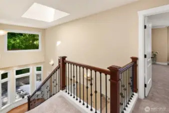 Stunning wrought iron staircase framed by soaring picture windows and a large skylight.