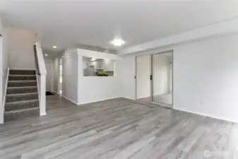 Open living room with stairs that go up to bedrooms and door to sunroom