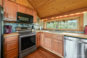 Stainless steel appliances including dishwasher, microwave, and range.  Utility room with washer and dryer downstairs.