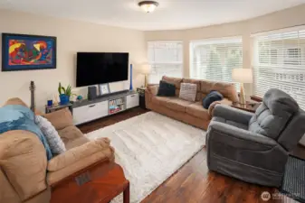 Open floor plan welcomes you into a spacious living room framed by expansive bay windows that flood the space with natural light.