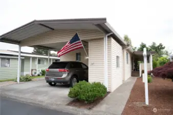 Facing south from the street. Side by side carport parking.