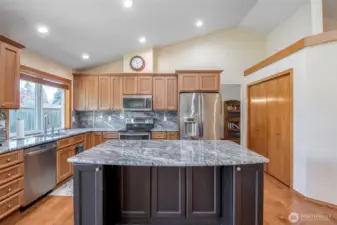 Updated kitchen displays attention to detail with newer cabinets w/extra large island, stunning granite countertops and backsplash, stainless steel appliances, range has double ovens, vaulted ceilings and open shelf above pantry for decor.