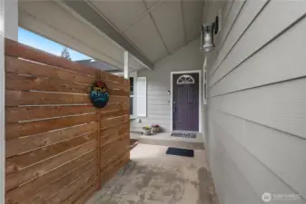 Entry way covered and privacy fence and shrub.