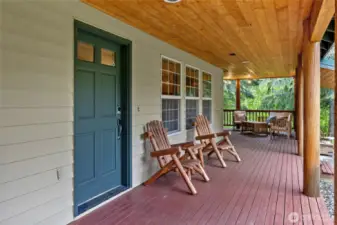 Covered wrap-around porch, elegantly framed by exposed wooden beams.