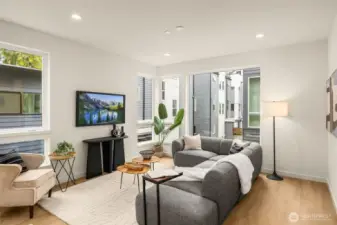 Spacious open-concept living room boasting oversized windows and elegant hardwood flooring