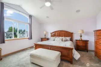 Primary bedroom is light and bright with a vaulted ceiling.