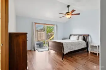 Primary bedroom with sliding glass door leading out back to a patio area.