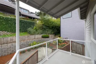 The covered balcony on the back of the home with a lovely view of the garden space.