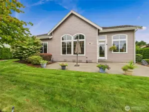 Beautifully landscaped backyard patio area with fruit trees, raised garden beds and roses.