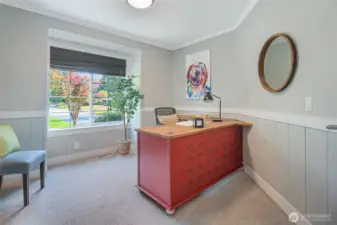 An office with built-in desk and shelving is conveniently located on the main floor. Custom wainscotting adds a nice design detail.