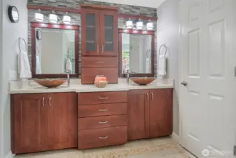 Custom cabinetry, solid surface counters and designer vessel sinks add to the lavish feeling in the primary bath.