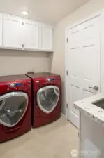 The main-level utility room features storage cabinets, and laundry sink with a new quartz countertop and sink.