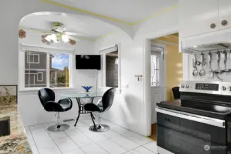 Downstairs to the light and bright kitchen with dramatic white tile floor and black stove and refrigerator. Corner dining nook with windows  allows maximum natural light.