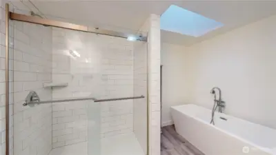 Spa-inspired master bath featuring a walk-in shower, classic white subway tile, and a freestanding soaking tub. Skylight fills the space with natural light.