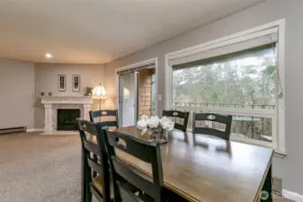 Open living and dining space with sliding glass doors leading to a private balcony surrounded by greenery.
