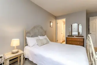 “Bright primary bedroom with soft natural light, neutral tones, and space for a queen or king bed.