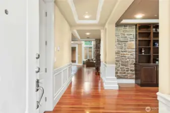 Upon entry, a formal living room with custom built-in cabinetry and shelving is located to the right. To the left, a versatile bonus room offers the perfect space for a home gym, music studio, or hobby room.