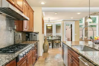 Chef’s kitchen featuring a Jen air 6-burner range with griddle, built-in GE Monogram refrigerator, wall oven and microwave, two Bosch dishwashers, beverage refrigerator, pot filler, and a built-in desk area.