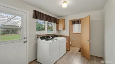 Spacious utility/mud room with backyard and garage access, featuring a convenient half bath