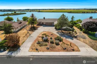 A flyover view of the property shows a large half-circle driveway with a large island of drough-resistant plants for our desert weather.  To the right of the home is access to Moses Lake and the second garage.