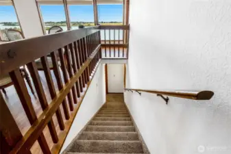 Here we go, down the carpeted stairs to the lower living area where you'll find another living room, three bedrooms, the second kitchen, more amazing views of the lake, the second fireplace, and the second garage/storage room.
