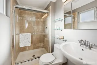 Ensuite 3/4 bath has tiled floors, tile pan to ceiling shower walls and glass shower doors. Pedestal sink. Window with rain glass lets in the southern exposure natural light.