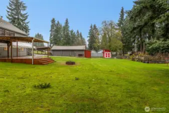 View of the covered deck, detached 2 car garage with the oversized carport, storage shed on the side of the garage, and the chicken coop has been converted to a very nice garden shed.