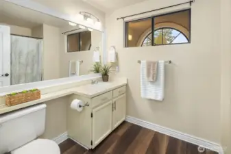 Upstairs second full bathroom with tub/shower combination, big mirror, and newer LVP flooring.