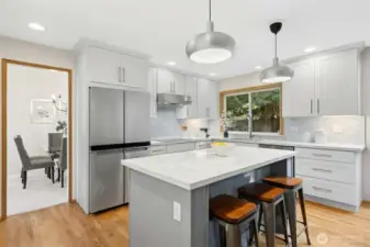 Stunningly updated kitchen featuring sleek stainless steel appliances and a sprawling quartz center island and counters, perfect for hosting festive gatherings.