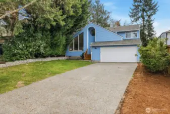 Welcome home to a light-filled exterior with a spacious driveway, 2-car garage, and beautiful mature trees that create a private, tucked-away feel.