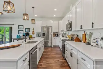 This kitchen is simply amazing! White cabinetry with crown moulding, black hardware, quartz countertops, stainless upgraded appliance package (brand new high-end dishwasher).  Pretty pendants and an ISLAND that is one heck of a seating bar - room for 8 at well over 10' long!!
