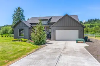 Concrete driveway with ample parking, rocked area for RV or extra parking.