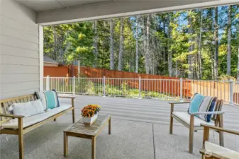 Covered patio overlooks the fenced backyard.
