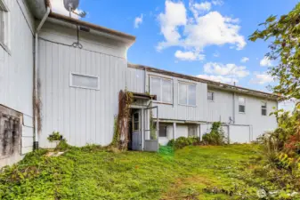 Rear exterior of the home with walkout access and surrounding greenery.