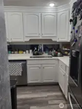 Entrance to L shaped kitchen with windows to the fenced patio space.