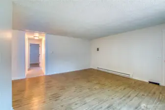 The living area leads into the hallway with new LVT flooring that resembles porcelain tiles.