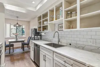 Nicely updated kitchen with a tile backsplash, deep stainless steel sink, newer appliances, updated lighting, and both open and closed shelving.