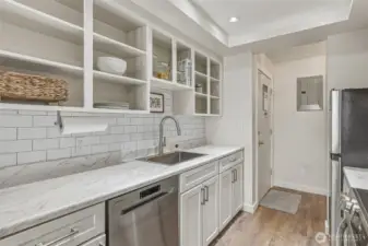 View towards the front door. This kitchen has a surprising amount of storage space. Note the recently upgraded electrical panel to the right of the front door. The seller spent over $8,000 in improvements, including new grounded outlets throughout the home, providing enhanced functionality, safety, and peace of mind.
