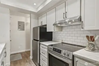 Bright and updated kitchen featuring a newer stove and range with vent hood, refreshed cabinet doors, and a modern refrigerator.