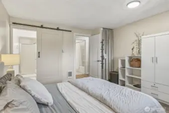 Primary bedroom with ensuite 3/4 bath on the left, looking towards guest bath across the hall (upper middle of picture). The electric water heater is behind the curtain to the right of the door to the hall.