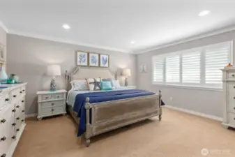 Primary bedroom with golf course views, recessed lighting, crown molding and custom plantation shutters.