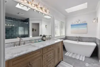 Modernized primary bathroom with dual sinks, marble countertops, free standing soaking tub and heated floors.