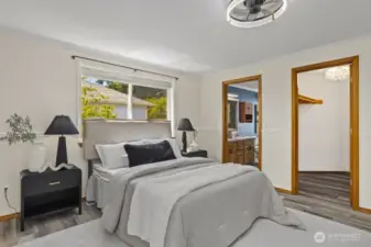The door to the left leads to the primary bathroom, and the door to the right leads to the walk-in closet with hanging space and shelves on both long walls.