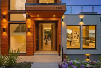 An inviting entry framed in warm wood and glass, opening to artful interiors and a glimpse of Lake Washington beyond