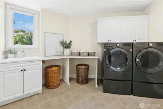 Bright and functional, the laundry room features stylish cabinetry, a folding station, and a separate storage nook for easy access.