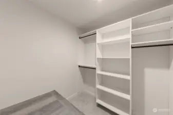An ample walk-in closet with custom shelving, a pleasant storage space, and a built-seating area.