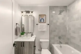Contemporary bathroom featuring stylish grey tile, modern fixtures, and a combined shower and bathtub for a sleek, functional design.